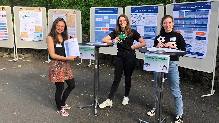 3 students in front of the posters with immunological content.