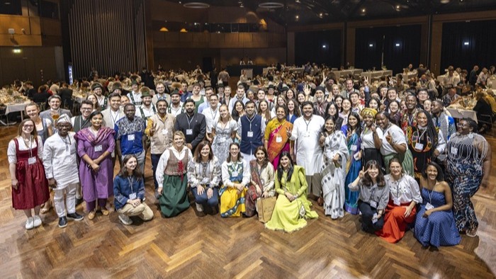 A group of young people in traditional costumes in a large hall.