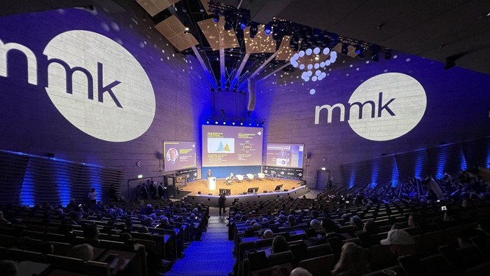 The picture shows the lecture hall of the TU Munich with the MMK logo