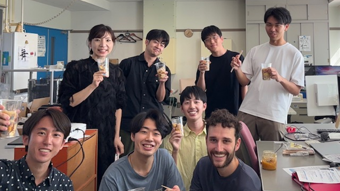 A group of people with drinks in a workroom.