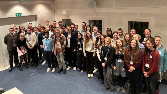 A large group standing close together in a conference room for a group photo.