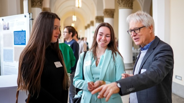 Ein älterer Herr im Gespräch mit zwei jungen Damen.