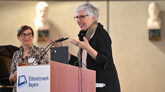 A woman is standing at a lectern delivering her keynote speech