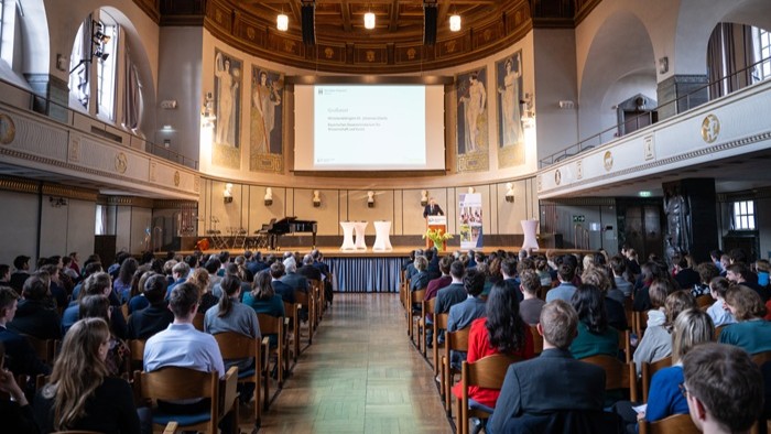 © MMerz Eine Präsentation in einem großen Saal mit vielen Zuhörern.