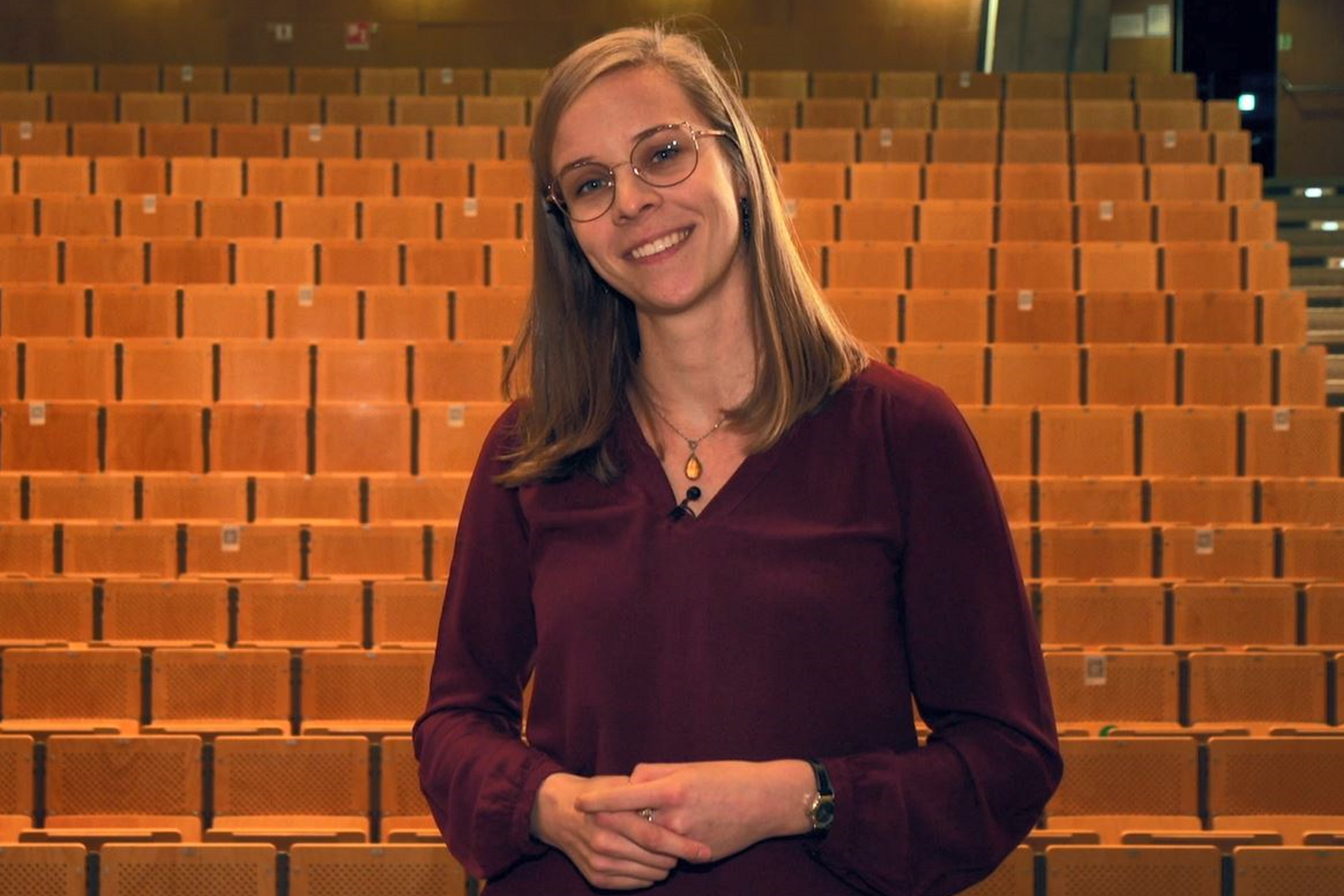 A woman gives a talk in an empty lecture hall.