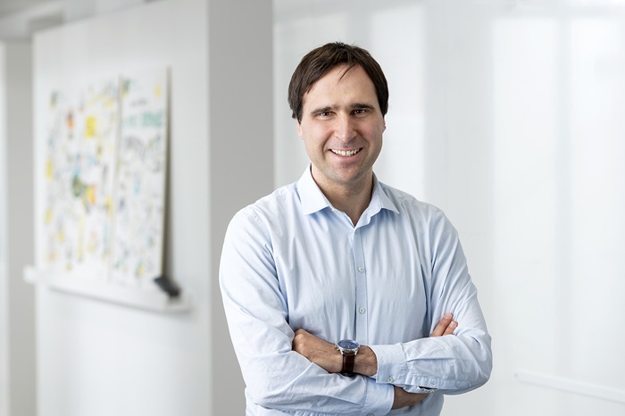 A man in a white shirt is smiling into the camera.