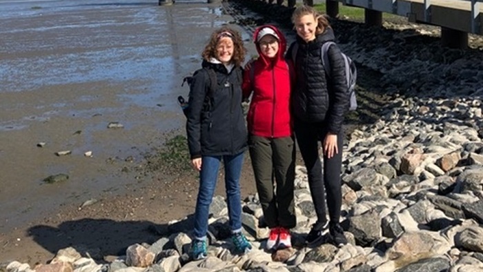 Three participants of the excursion stand in front of the Wadden Sea.