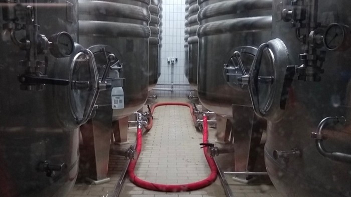 Vier schwarze Brautanks auf jeder Seite eines Korridors in einer Brauerei.