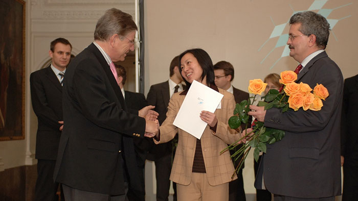 Wissenschaftsminister Dr. Thomas Goppel überreicht einer jungen Frau eine Urkunde.