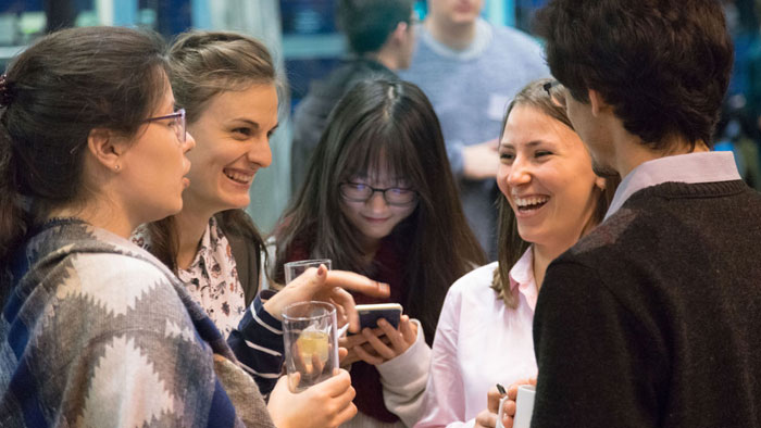 Students stand together, laughing and joking with one another.