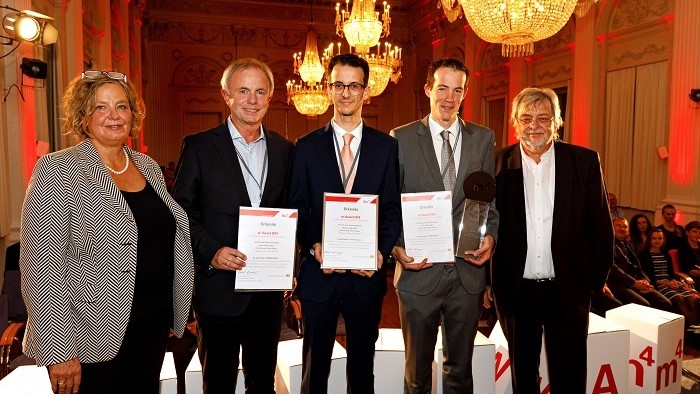 Three scientists have a certificate in their hands and smile into the camera