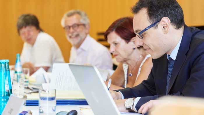 Members of a committee listen intently and take notes. 