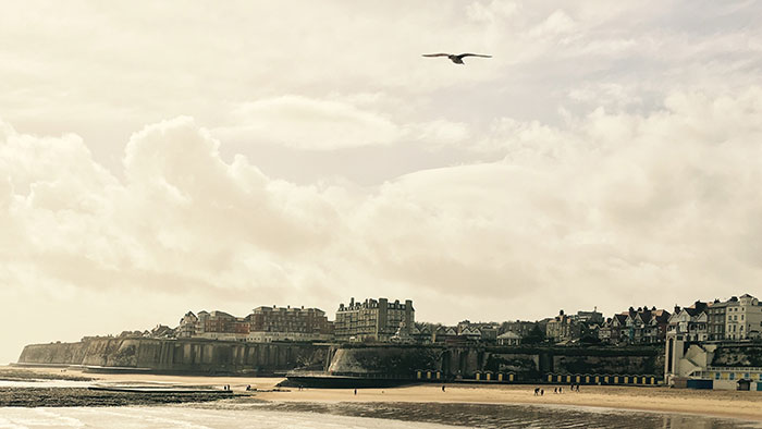 Landscape picture: A coastal city next to a wide sandy beach.