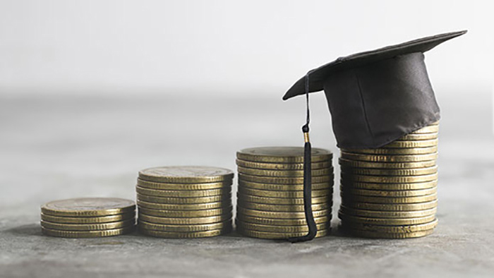 Several stacks of coins are placed on a surface. They are arranged in height order. A mortarboard sits on top of the final stack of coins.