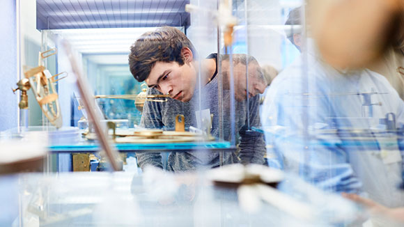 A young man looks into a glass cabinet with interest and concentrates on an exhibit.