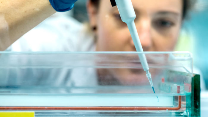 Eine junge Frau arbeitet in einem medizinischen Labor mit einer Pipette.