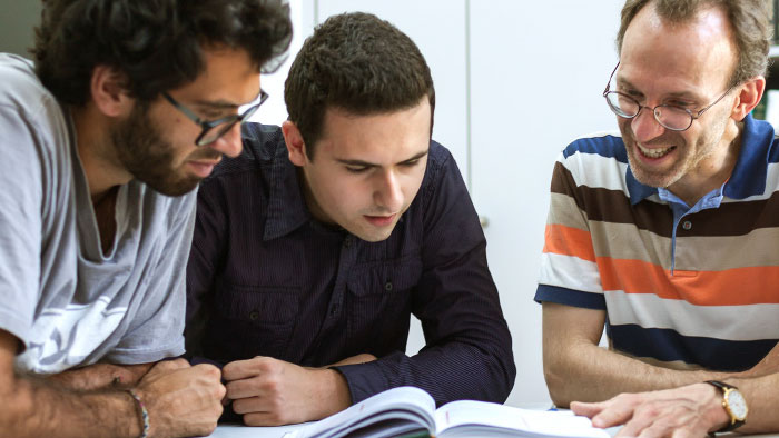 Several people read a book together with interest.