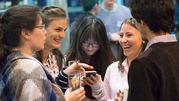 Four young women and a young man laughing and joking together.