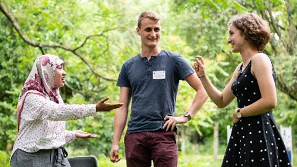 Three young people engage in a lively discussion outdoors.