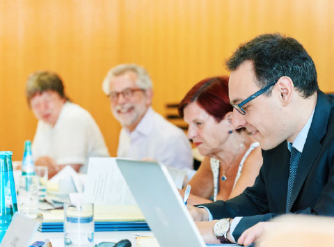 Members of a committee listen attentively and take notes. 